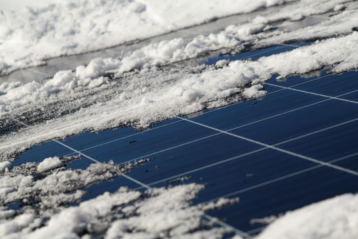  Fotowoltaika produkuje prąd zimą, panele słoneczne pokryte lekkim śniegiem generują energię elektryczną.